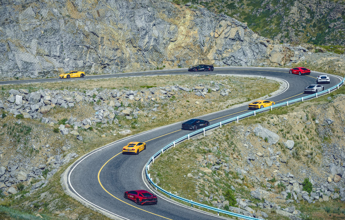 Convoy of Lamborghinis on a uphill winding road